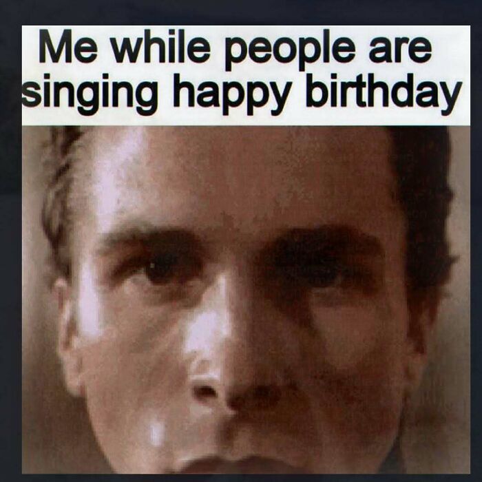 A close-up of a man's face with a neutral expression, captioned Me while people are singing happy birthday, capturing unhinged pics.