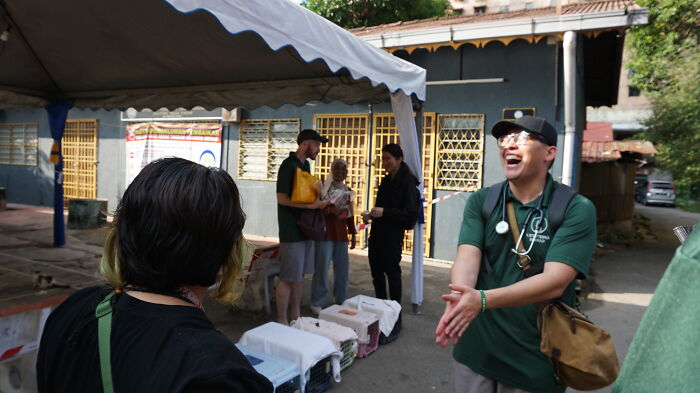 Organization members helping street cats with local action and clever technology use, standing under a white tent.