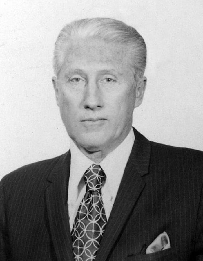 A black and white portrait of a man in a suit and patterned tie, connected to solved mysteries.