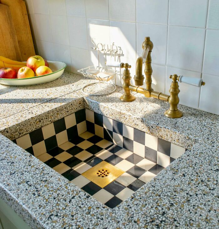 Kitchen sink with black and white checkered tile interior design and brass faucet