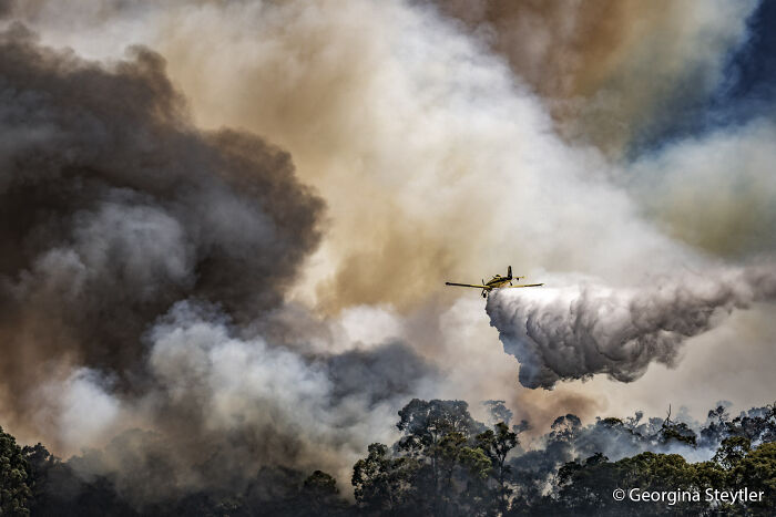 An aerial firefighting plane dropping retardant over a wildfire in Australia, part of the Au Photo Contest.