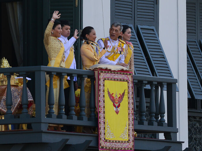 Thai royal family members waving from balcony during ceremony Thai royal family members waving from balcony during ceremony