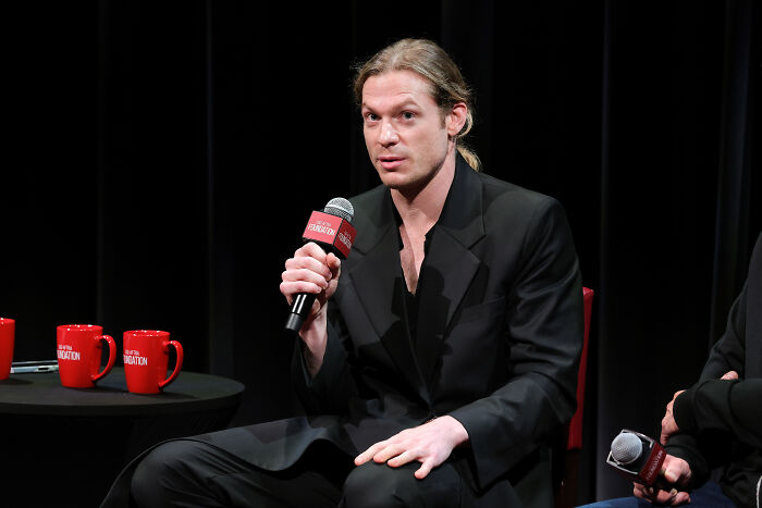 AMC show star at an event, holding a microphone while speaking, engaging fans.