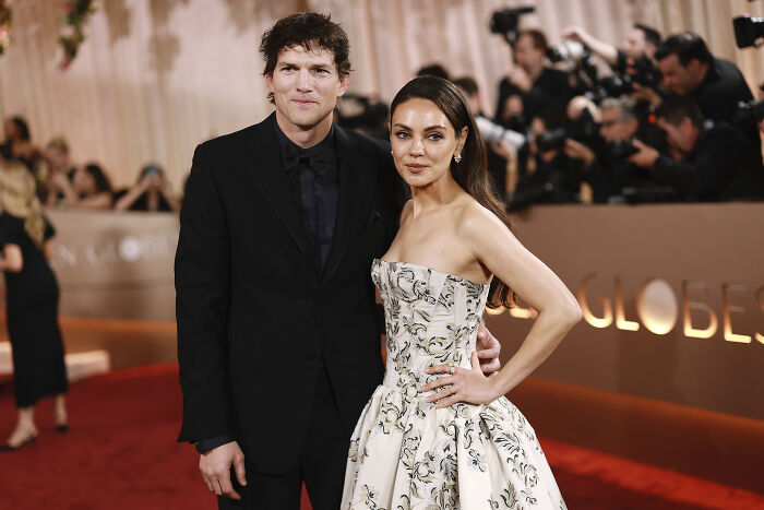 Ashton Kutcher and Mila Kunis, celebrities, posing on a red carpet with their fame still intact.