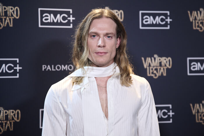 AMC show star on a red carpet with an AMC+ backdrop, wearing a white shirt, captivating fans.