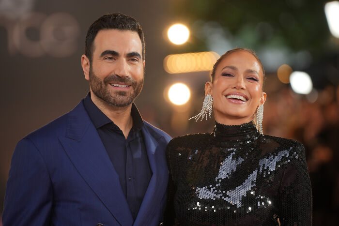 Jennifer Lopez smiling in a black sequin dress at a red carpet event with a man in a blue suit Jennifer Lopez smiling in a black sequin dress at a red carpet event with a man in a blue suit