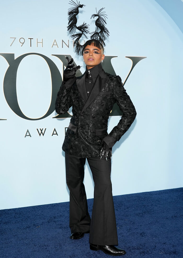 Man in black textured suit with avant-garde feathered headpiece at Tony Awards