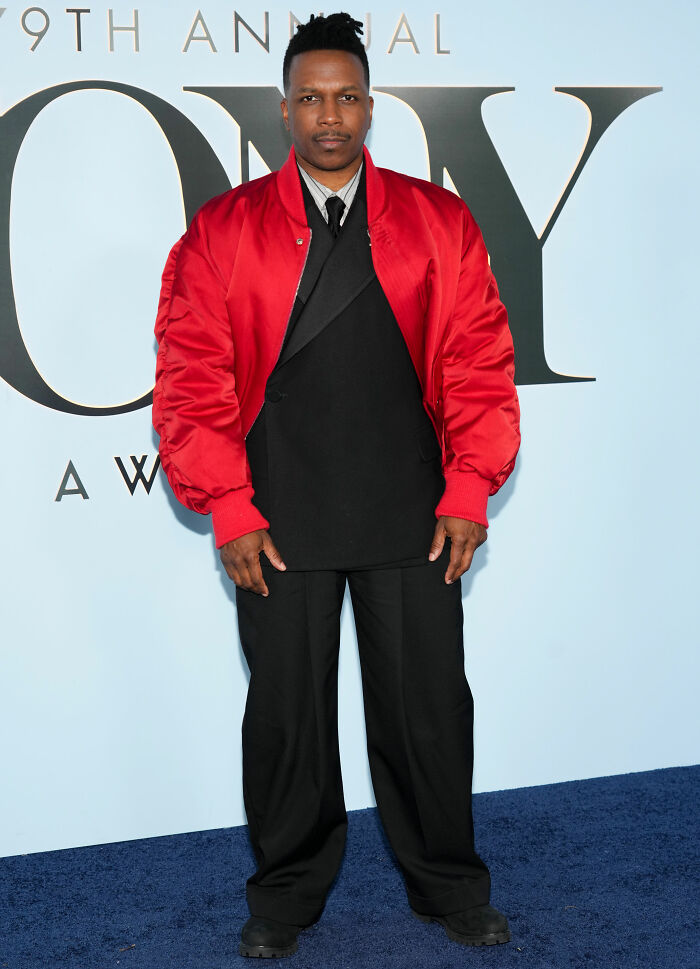 Man wearing a red satin jacket with black pants on the Tony Awards red carpet