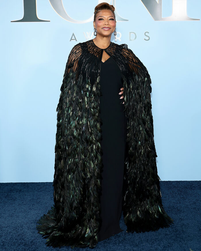 Woman wearing feathered cape black dress at Tony Awards