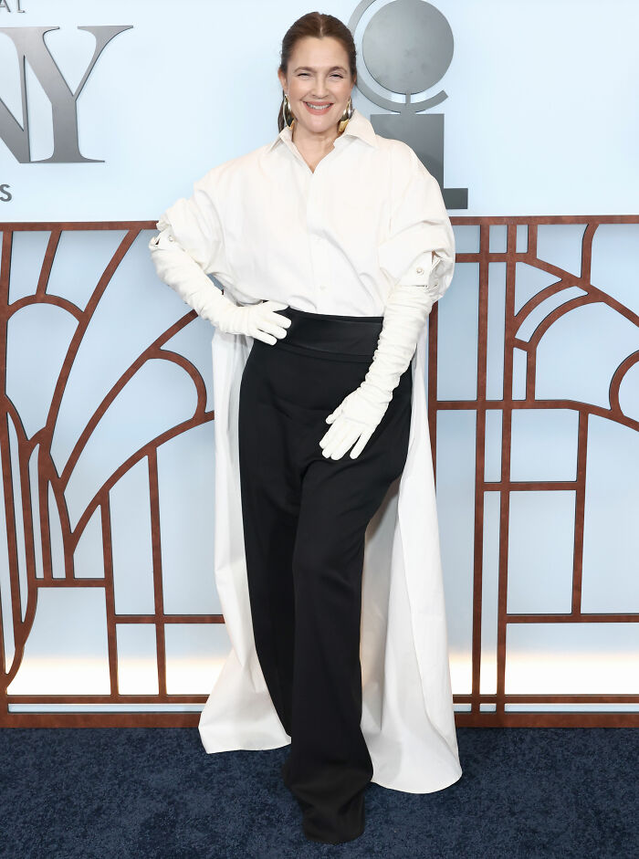 Woman in white cape shirt and black pants with gloves at 2026 Tony Awards fails
