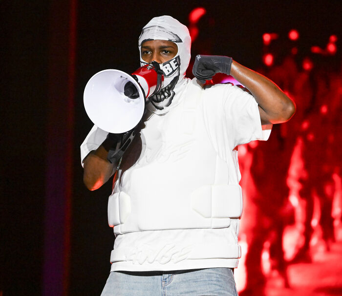 Rihanna's partner onstage, wearing a mask and white vest, holding a megaphone, accused of disrespecting her.