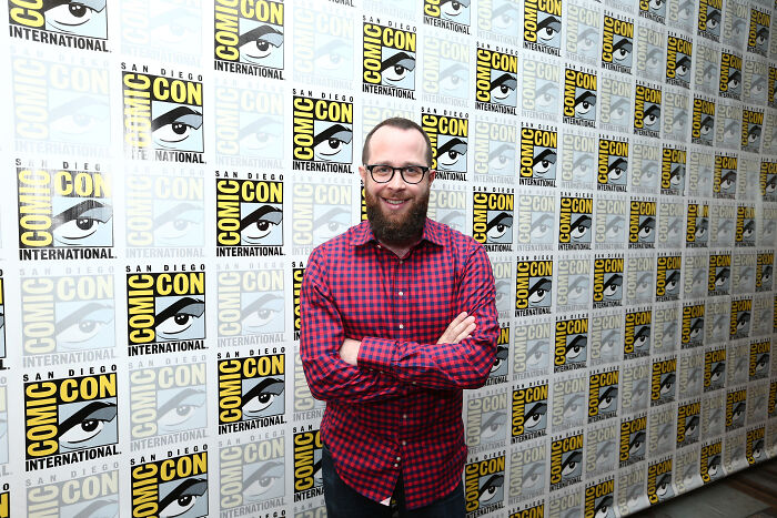 Man with glasses and beard posing at San Diego Comic-Con event background Man with glasses and beard posing at San Diego Comic-Con event background