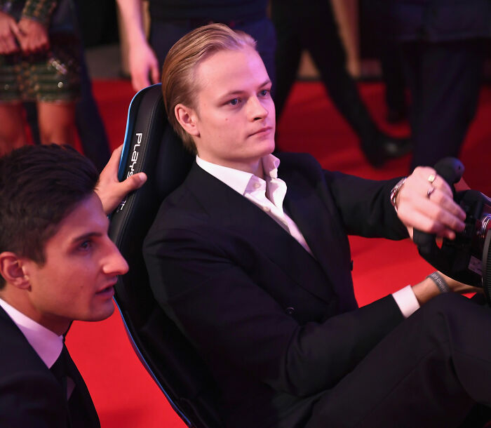 Norwegian Crown Princess's son in black suit sitting in racing seat at event Norwegian Crown Princess's son in black suit sitting in racing seat at event