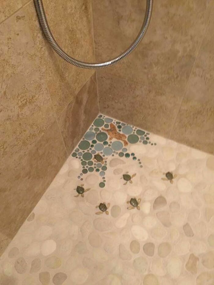 Bathroom shower floor with creative tile design featuring turtles and pebbles