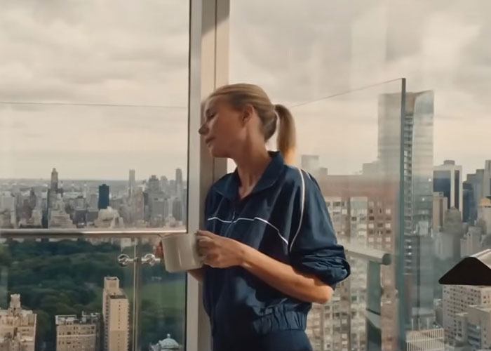 Woman in blue jacket holding coffee mug by a city window Woman in blue jacket holding coffee mug by a city window