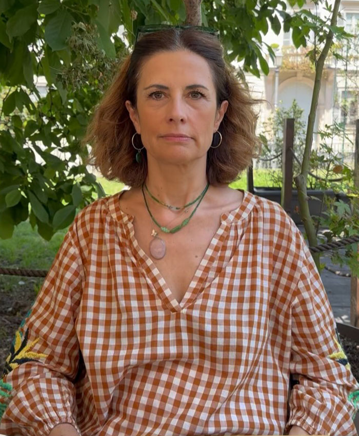 Colin Firth's ex-wife wearing checkered blouse sitting outdoors with trees Colin Firth's ex-wife wearing checkered blouse sitting outdoors with trees