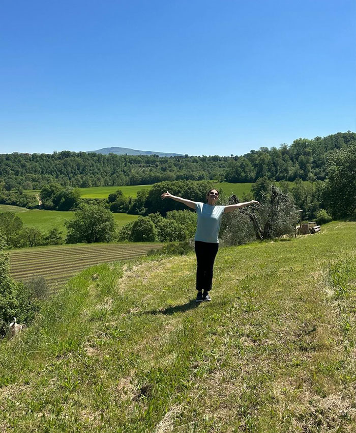Woman standing with arms wide open in green countryside under blue sky Woman standing with arms wide open in green countryside under blue sky