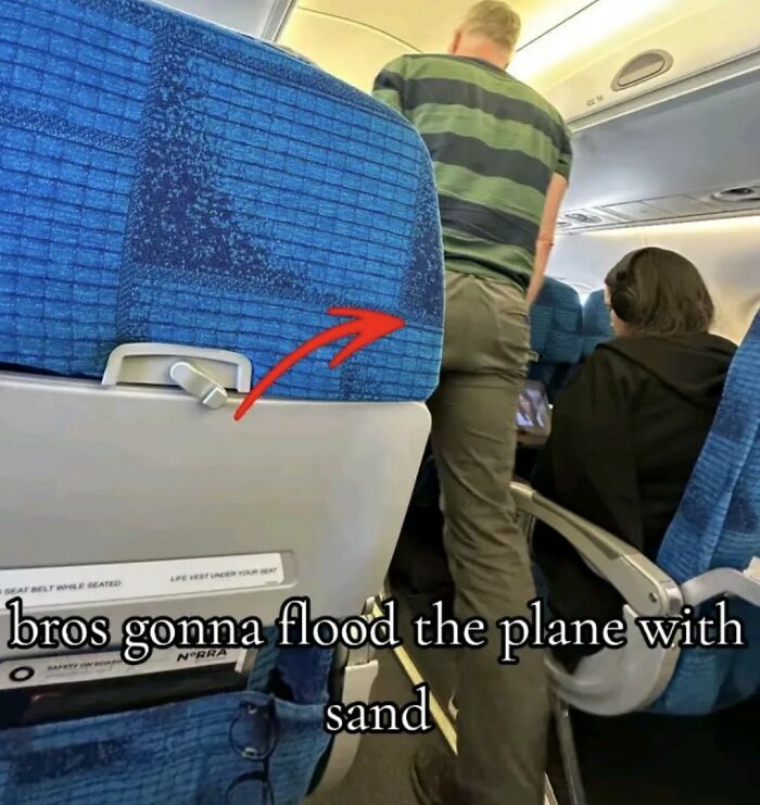 A cringe man on an airplane with a wet patch on his pants.