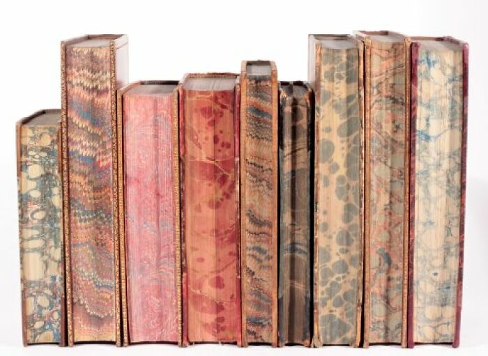 A row of old books with marbled covers, still intact after many years, showcasing historical binding art.