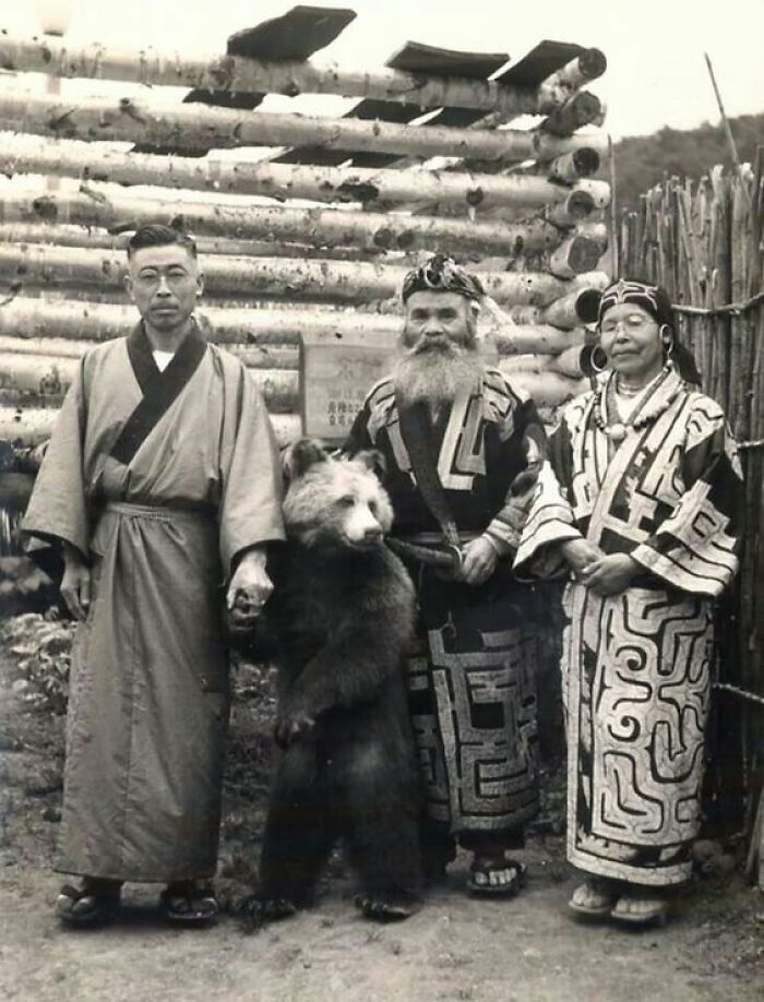 A black and white photo of three individuals with a small bear, an interesting photo still intact after all these years.