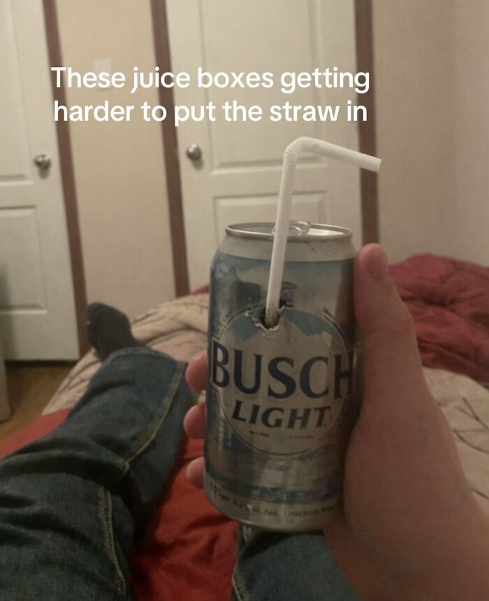 A person holds a Busch Light can with a straw, a cringe image. The straw is piercing the can, appearing like a juice box.
