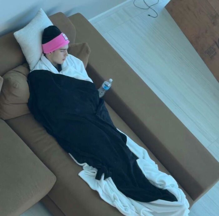 Person wrapped in blanket resting on couch after Looksmaxxer Clavicular surgery