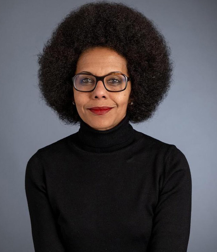 A portrait of Paris Deputy Mayor, a woman with an afro and glasses, looking directly at the camera, related to the climate crisis. A portrait of Paris Deputy Mayor, a woman with an afro and glasses, looking directly at the camera, related to the climate crisis.