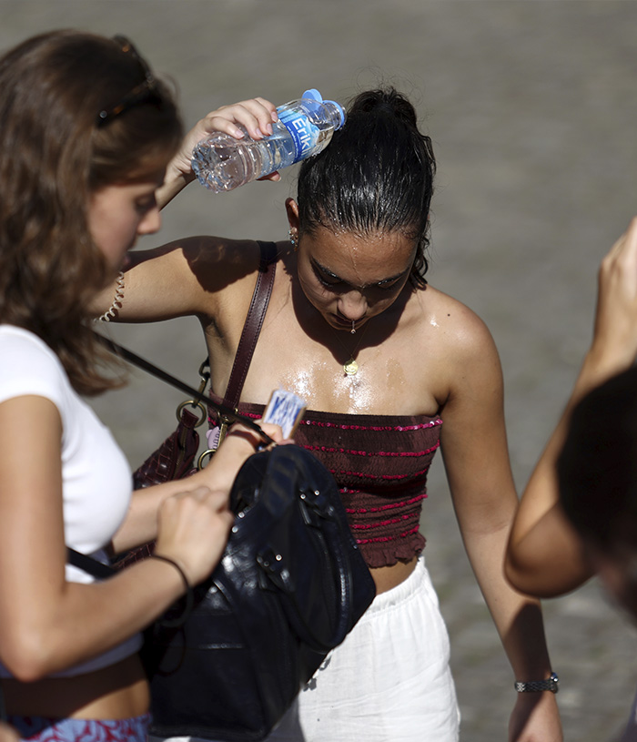 A young woman pours water on her head to cool down during Europes climate crisis heat wave. A young woman pours water on her head to cool down during Europes climate crisis heat wave.