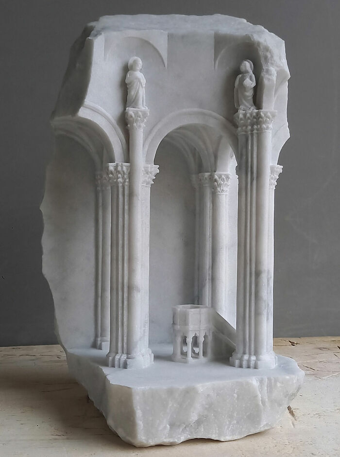 Artist carves tiny architectural models of ancient buildings into solid stone, showing figures and detailed pillars.