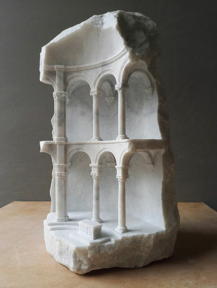 Artist carves tiny architectural models of classical buildings into solid stone, presenting an elegant two-tier arcade.