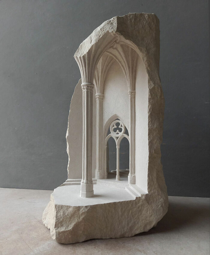 Artist carves tiny architectural model of an ancient building in solid stone, depicting an arched interior.