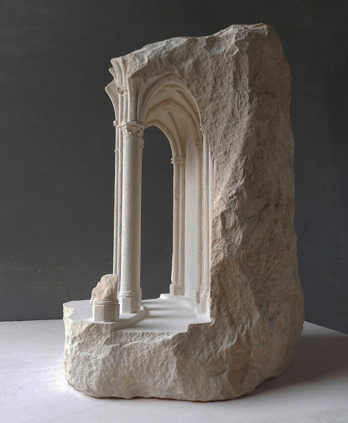 Artist carves tiny architectural models of ancient and classical buildings into solid stone, depicting an arched walkway.