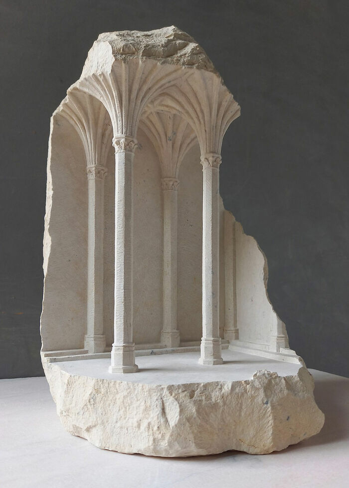 Artist carves tiny architectural models of classical buildings into solid stone, showcasing a vaulted ceiling.