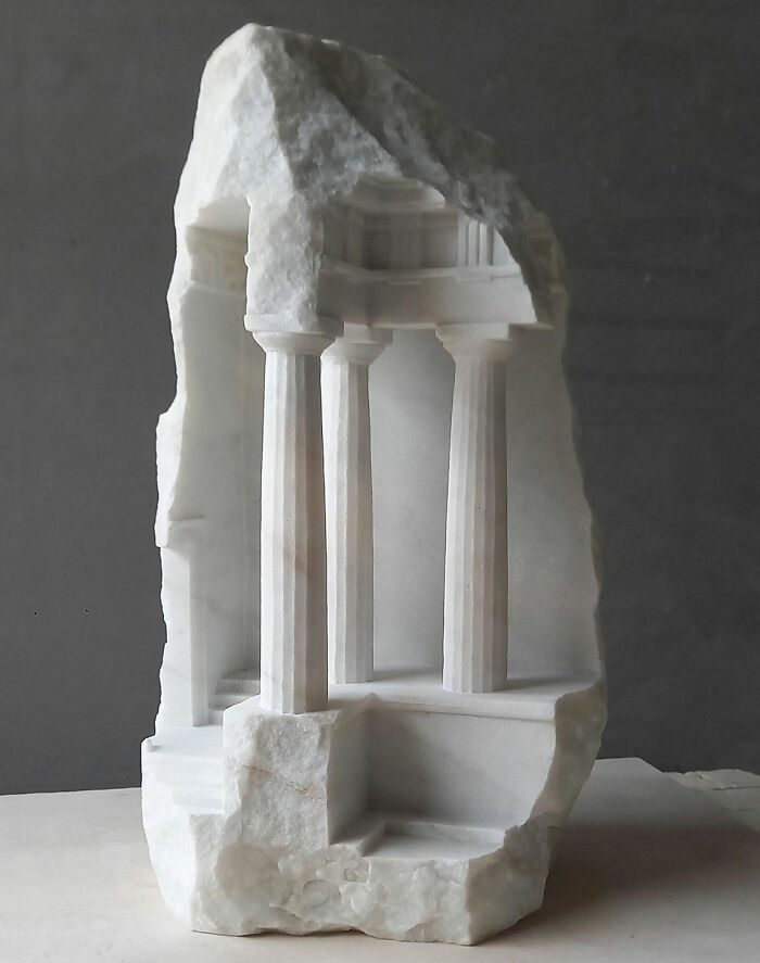 Artist carves a tiny architectural model of a classical building with columns into solid stone, a stunning miniature.