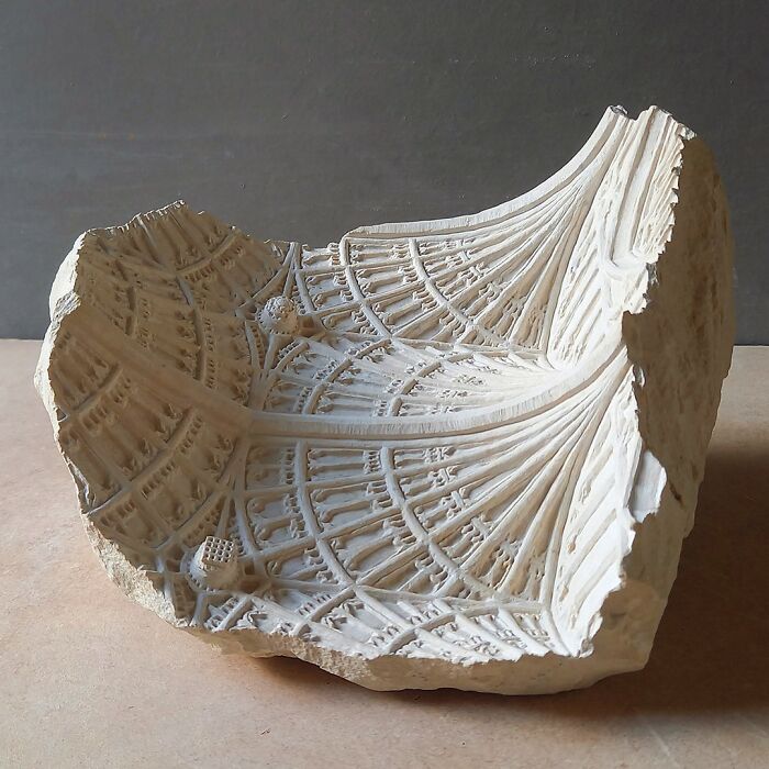 Artist carves a tiny architectural model of an ancient building into solid stone, showing a complex ceiling.