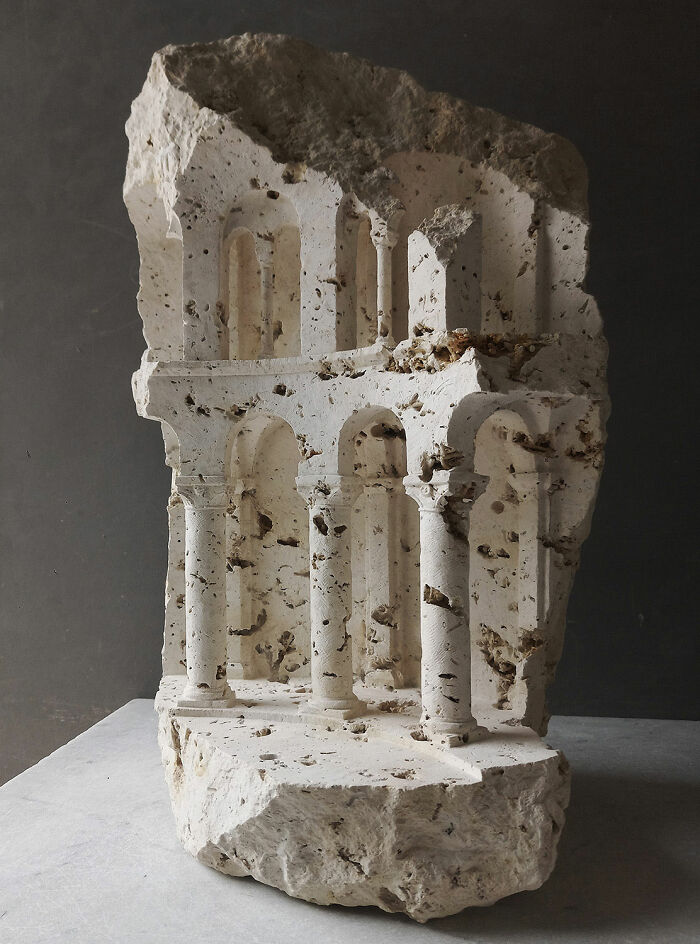 Artist carves a tiny architectural model of an ancient building into solid stone, showcasing intricate details.