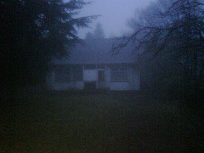 Creepy photo of an abandoned house in foggy dark forest setting