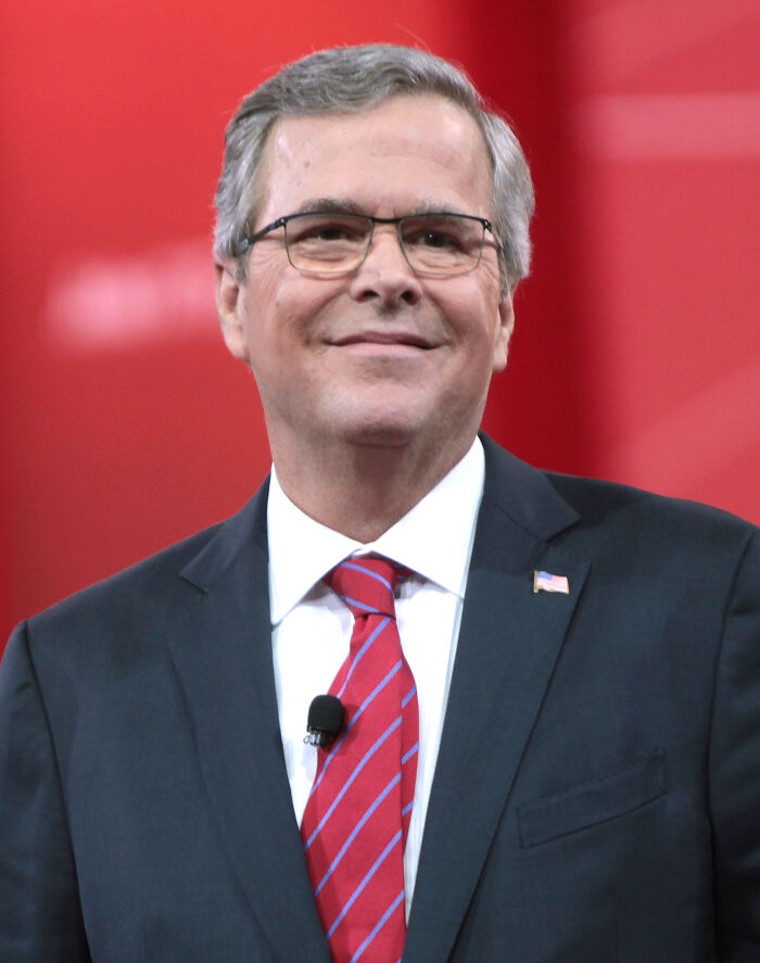 Jeb Bush smiling at a podium, a figure often involved in political celebrity scandals.