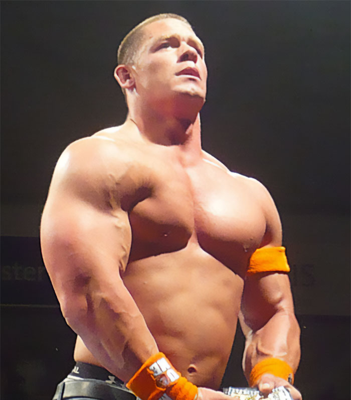 John Cena looking up with a serious expression, showcasing his muscular physique during his wrestling career.