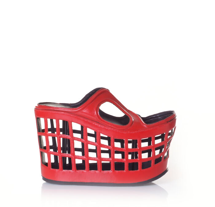 A red creative shoe by Kobi Levi designed to resemble a shopping basket, with a grid pattern and handle.