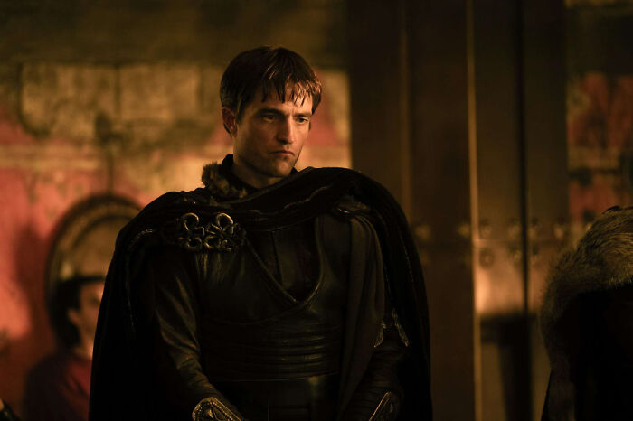 Man in dark medieval armor and cloak inside dimly lit room in The Odyssey Man in dark medieval armor and cloak inside dimly lit room in The Odyssey