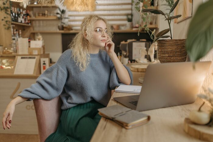 A thoughtful woman with curly blonde hair working on a laptop, contemplating general knowledge questions. A thoughtful woman with curly blonde hair working on a laptop, contemplating general knowledge questions.