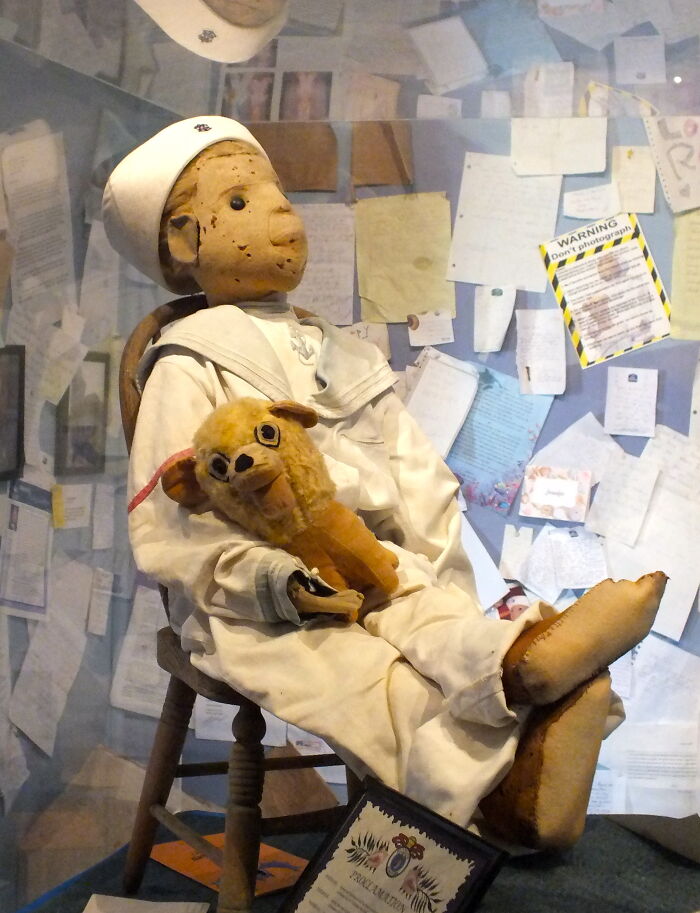 A creepy doll, Robert the Doll, sitting on a chair, part of 55 experiences people can't explain.