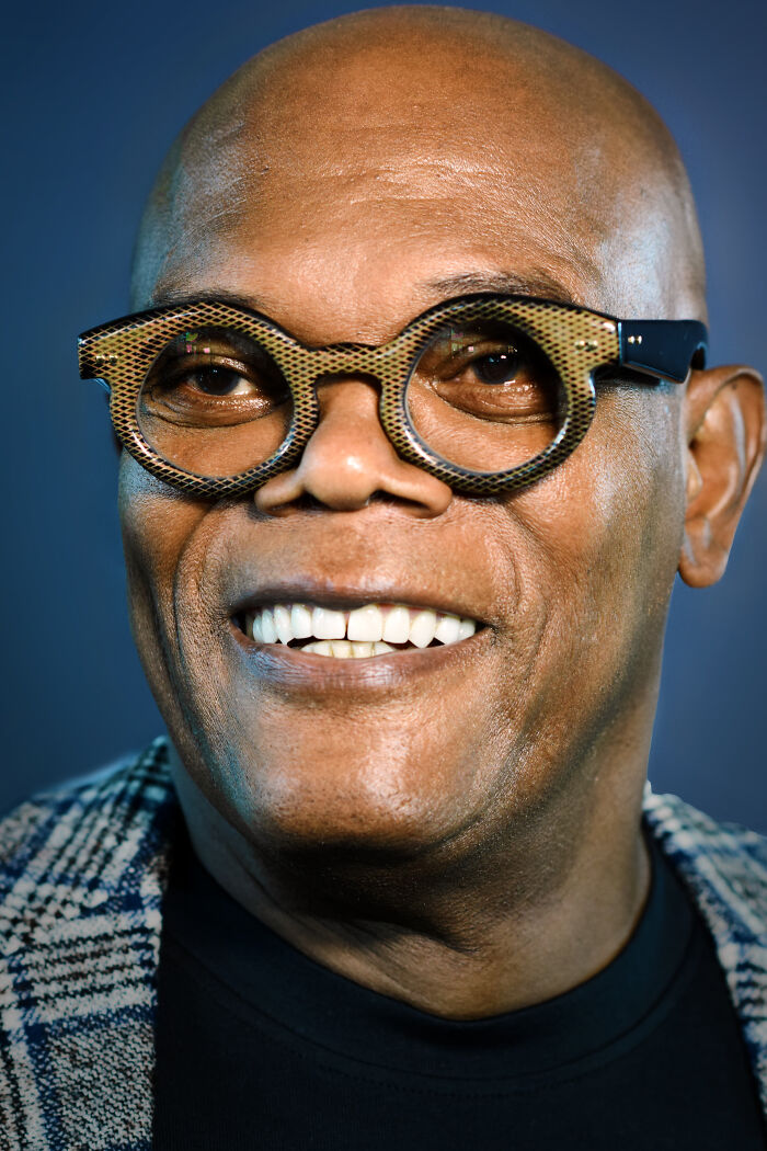 Close-up of Samuel L. Jackson smiling, wearing unique glasses, a celebrity with interesting useless facts.