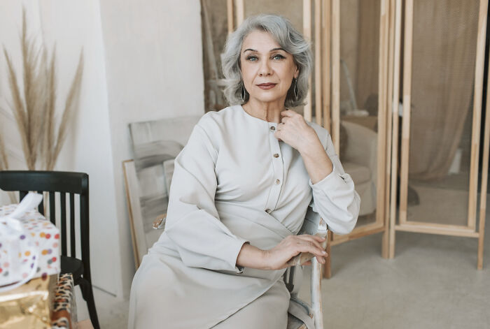 Elegant older woman sitting in light dress