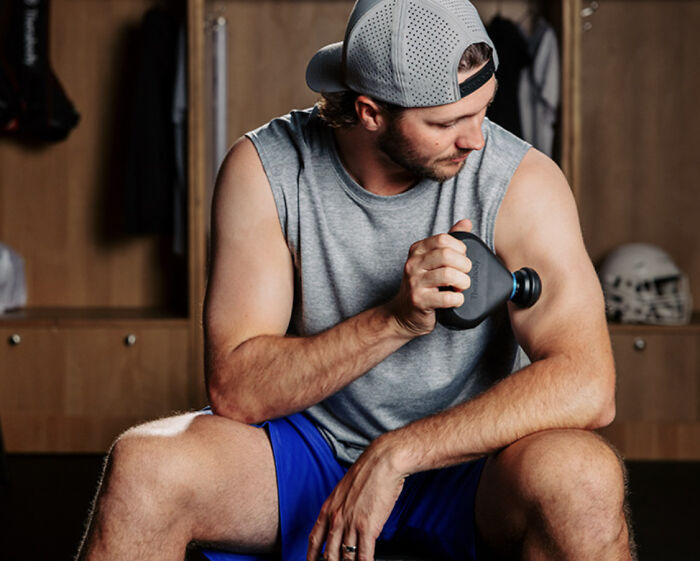 Man using portable massage gun as practical Father's Day gift for muscle relief