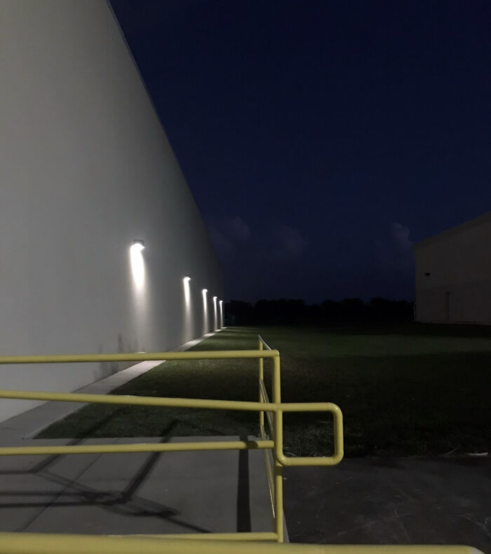 An exterior view of a building at night with bright lights along the wall, a haunting liminal space.