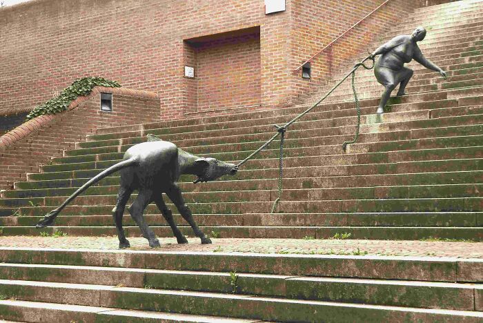 Creative sculpture of a dog pulling a person up stairs showcasing designer genius
