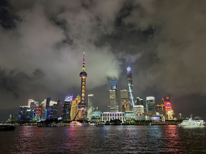 The vibrant Shanghai skyline at night, showcasing illuminated skyscrapers and the iconic Oriental Pearl TV Tower across the river in China.