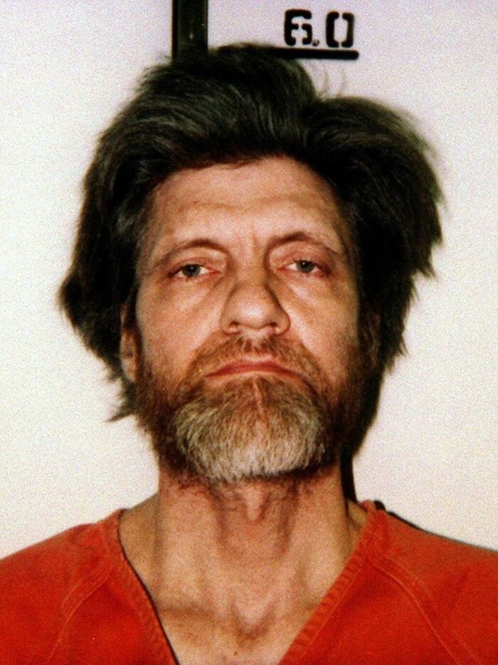 A mugshot of a man with a beard and disheveled hair, representing an individual from unsolved mysteries.